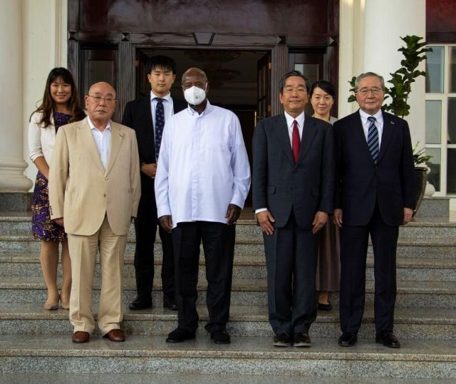 Officials and visitors pose for a group photograph on the steps of a building